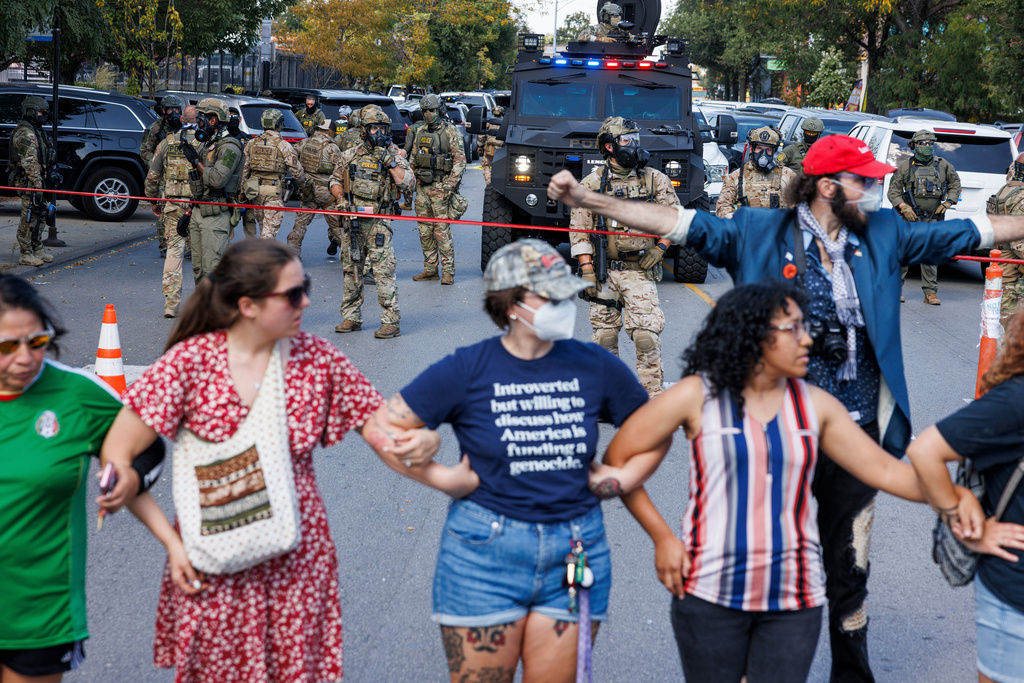 Protestors create a line to maintain distance between ICE officers and protestors in the Brighton Park neighborhood of Chicago, on Saturday, Oct. 4, 2025, after protesters learned that U.S. Border Patrol shot a woman Saturday morning on Chicago's Southwest Side. (Anthony Vazquez/Chicago Sun-Times via AP)