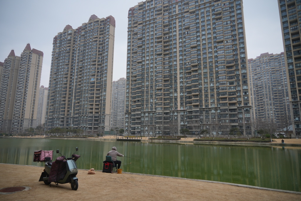 Residents play with their children in a playground at the semi-abandoned "Life in Venice" housing complex in Qidong, on China's east coast, Feb. 5, 2026. (AP Photo/Dake Kang)
