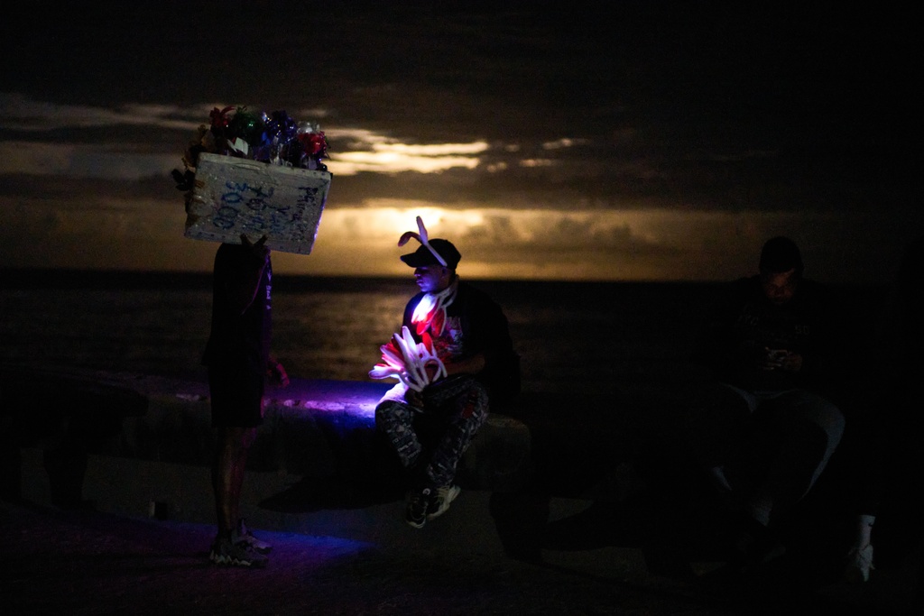 Street vendors chat on the Malecón during a blackout in Havana, Monday, March 16, 2026. (AP Photo/Ramon Espinosa)