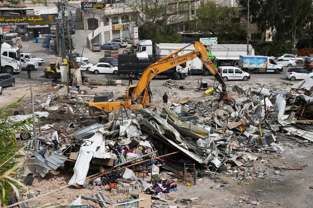 Residents inspect the site of an Israeli army demolition campaign that targeted several Palestinian commercial structures overnight, days after the issue of demolition and evacuation orders to owners, in the West Bank town of Al-Eizariya Tuesday, May 12, 2026. (AP Photo/Mahmoud Illean)