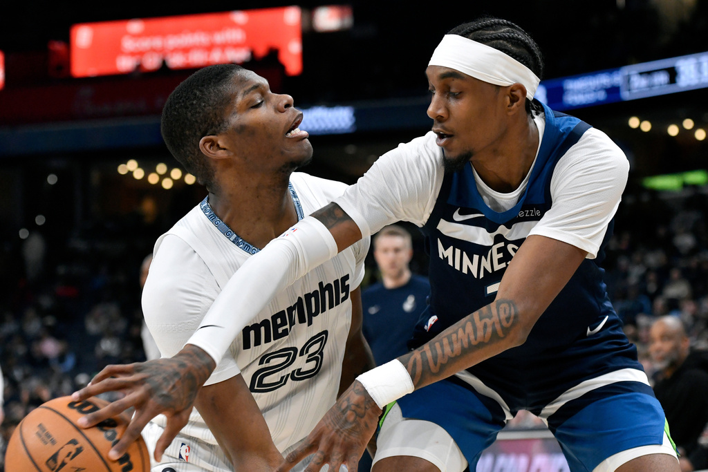 Minnesota Timberwolves forward Jaden McDaniels, right, passes the ball around Memphis Grizzlies forward Cedric Coward (23) in the first half of an NBA basketball game Monday, Feb. 2, 2026, in Memphis, Tenn. (AP Photo/Brandon Dill)