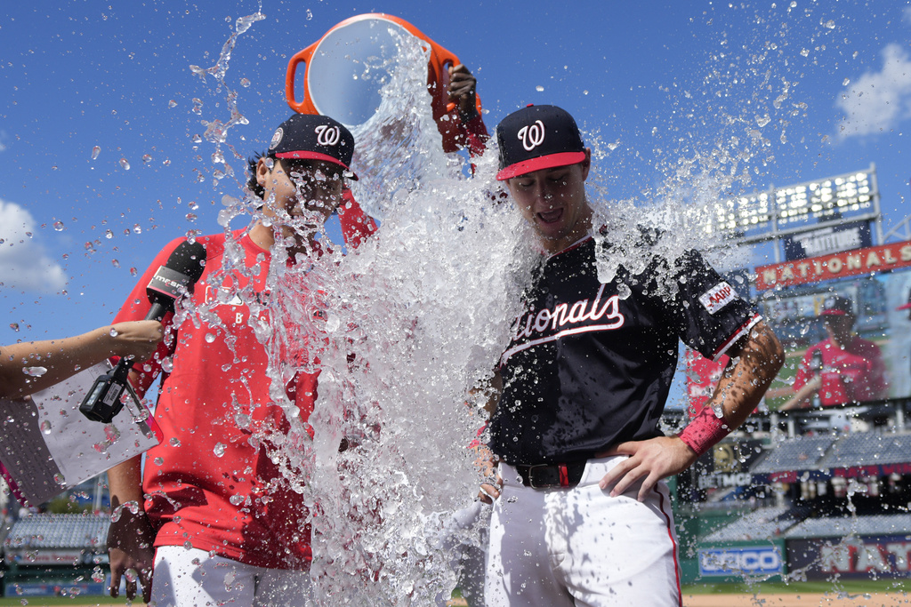 Washington Nationals starting pitcher Andrew Alvarez, left, and catcher CJ Stubbs get doused with water by Josh Bell after securing a win against the Miami Marlins in their major league debuts at Nationals Park, Monday, Sept. 1, 2025, in Washington. (AP Photo/Jess Rapfogel)