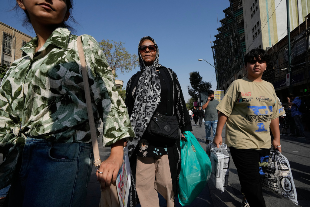 People carrying shopping bags walk through Tehran's Grand Bazaar in Tehran, Iran, Monday, Aug. 24, 2026. (AP Photo/Vahid Salemi)
