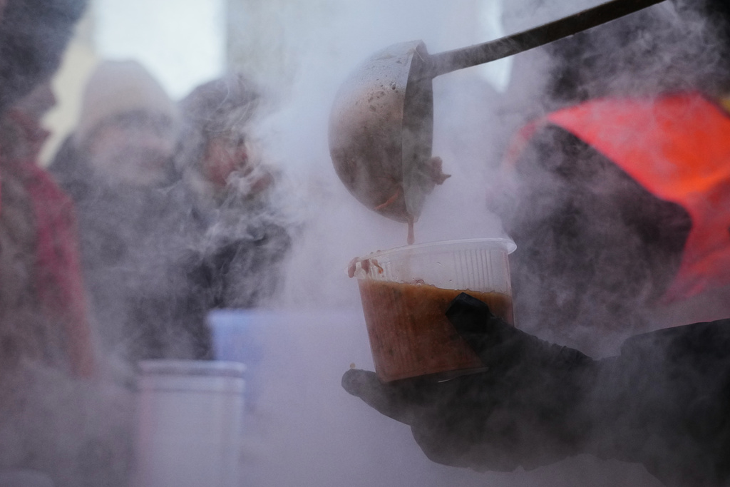 Volunteers serve free hot food to Kyiv residents during a blackout caused by Russia's regular air attacks on the country's energy system in Kyiv, Ukraine, Monday, Feb. 2, 2026. (AP Photo/Sergei Grits)