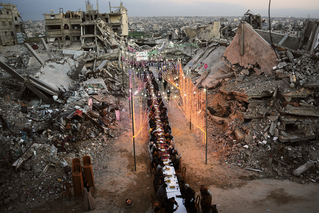 Palestinians sit at a long table amid the rubble of destroyed buildings as they gather for iftar, the fast-breaking meal, during the Muslim holy month of Ramadan in Khan Younis, Gaza Strip, Thursday, Feb. 19, 2026. (AP Photo/Abdel Kareem Hana)
