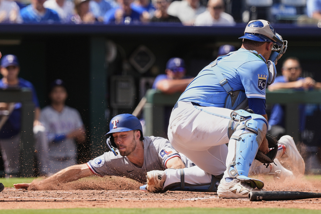 Texas Rangers' Evan Carter beats the tag by Kansas City Royals catcher Luke Maile to score on a two-run single hit by Josh Smith during the fifth inning of a baseball game Thursday, Aug. 21, 2025, in Kansas City, Mo. (AP Photo/Charlie Riedel)