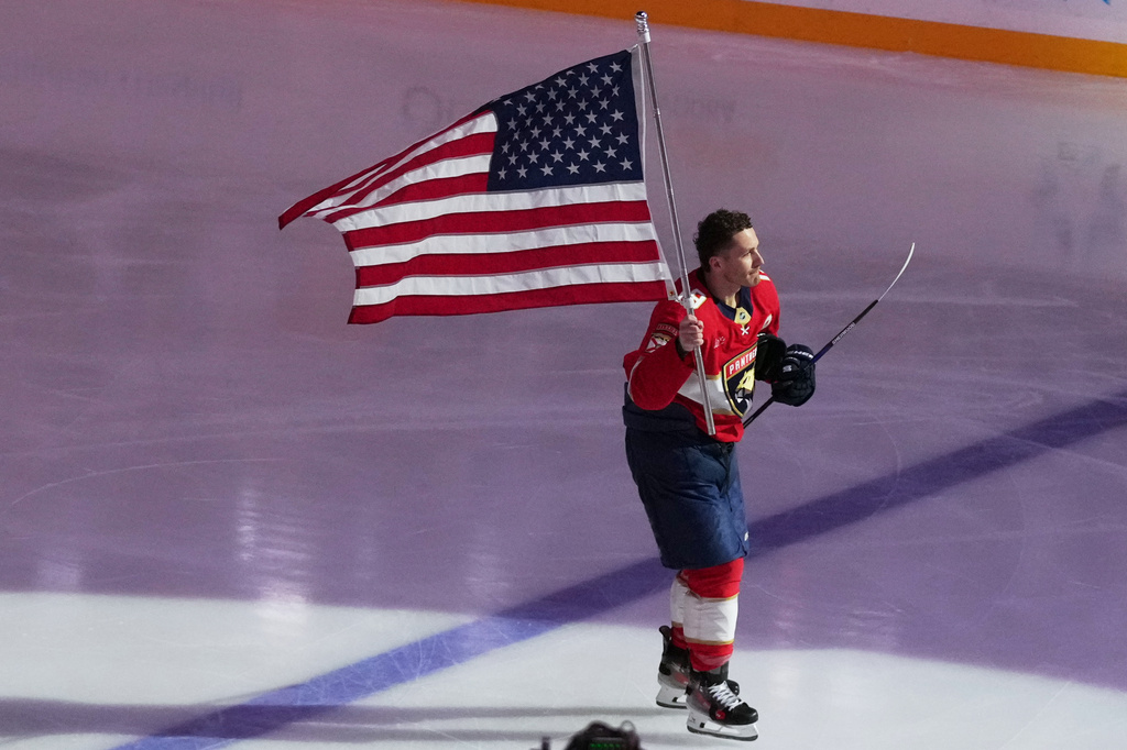 Florida Panthers left wing Matthew Tkachuk (19) skates with an American flag before an NHL hockey game honoring the players on the USA team winning the gold medal at the Milan Cortina Olympics,, Thursday, Feb. 26, 2026, in Sunrise, Fla. (AP Photo/Lynne Sladky)