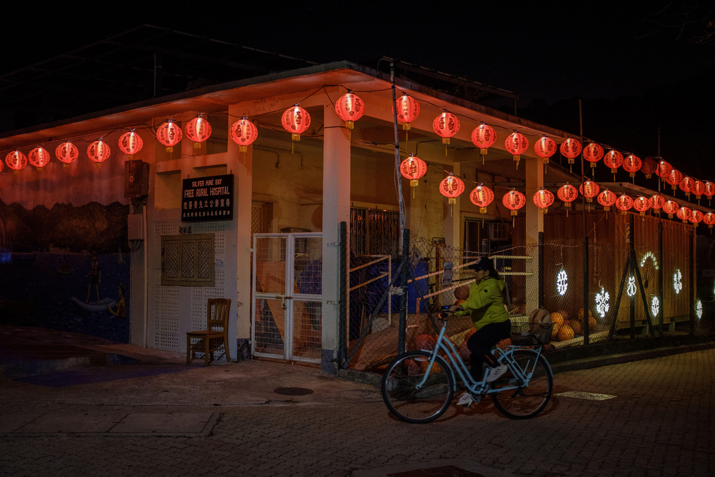A cyclist rides past a rural hospital decorated with red lanterns on the first day of the Lunar New Year in Hong Kong, Feb. 17, 2026. (AP Photo/May James)