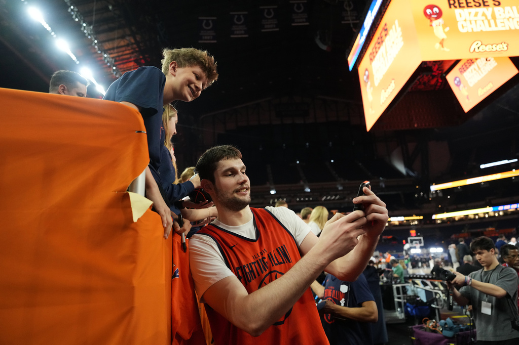 Illinois' Tomislav Ivisic takes a selfie with a fan following practice ahead of a national semifinal NCAA college basketball tournament game against UConn at the Final Four, Friday, April 3, 2026, in Indianapolis. (AP Photo/Michael Conroy)