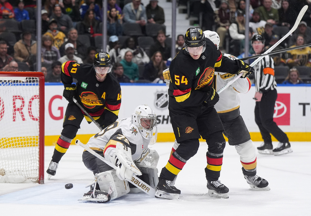 Vegas Golden Knights goalie Carter Hart (79) makes a save as Vancouver Canucks' Aatu Raty (54) watches the puck go wide of the net during the third period of an NHL hockey game, in Vancouver, British Columbia, Tuesday, April 7, 2026. (Darryl Dyck/The Canadian Press via AP)