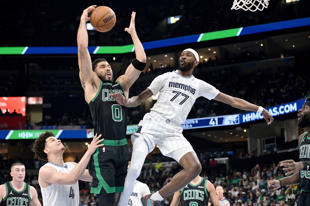 Boston Celtics forward Jayson Tatum (0) grabs the ball between Memphis Grizzlies guards DeJon Jarreau (77) and Walter Clayton Jr. (4) in the first half of an NBA basketball game Friday, March 20, 2026, in Memphis, Tenn. (AP Photo/Brandon Dill)
