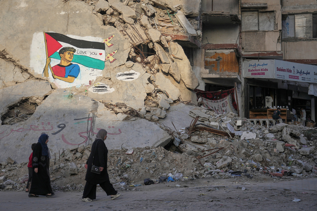 Women and children walk past a mural depicting FC Barcelona soccer player Lamine Yamal holding a Palestinian flag on the rubble of a destroyed building in northern Gaza City, Thursday, May 14, 2026. (AP Photo/Jehad Alshrafi)