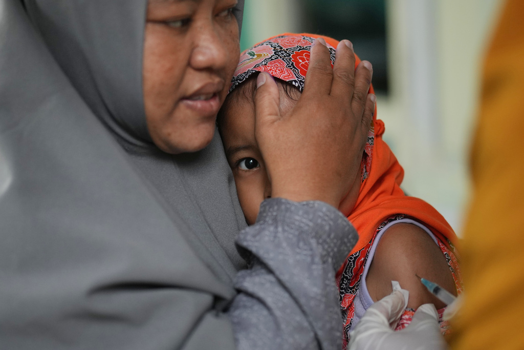 A young girl is comforted by her mother as she receives a measles vaccine during a vaccination campaign following an outbreak, at a kindergarten in Sumenep on Madura Island, Indonesia, Monday, Sept. 8, 2025. (AP Photo/Dita Alangkara)