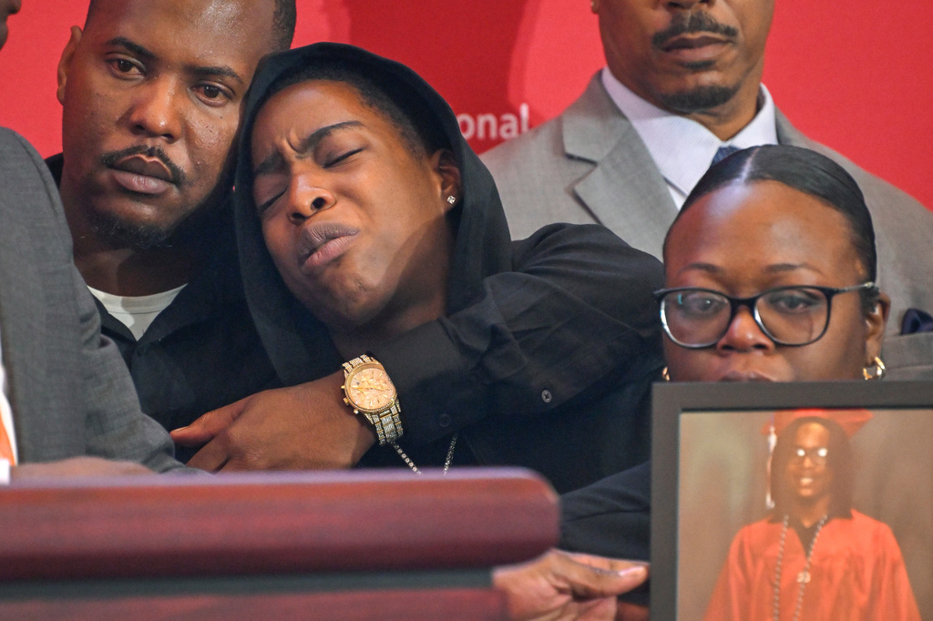 Azariah Mayhorn is comforted by uncle Trevon Petty, left, as her mother, Lynsey Smith, right, holds a photo of her deceased son and Mayhorn's sister, Tyler Smith, as they appear at the National Urban League's annual conference, Thursday, July 30, 2026, in Nashville, Tenn. (AP Photo/John Amis)