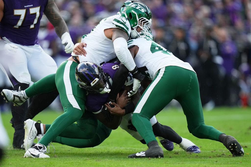 Baltimore Ravens quarterback Lamar Jackson, center, is tackled by New York Jets linebacker Jermaine Johnson, left, and New York Jets linebacker Jamien Sherwood, right, during the first half of an NFL football game, Sunday, Nov. 23, 2025, in Baltimore. (AP Photo/Stephanie Scarbrough)