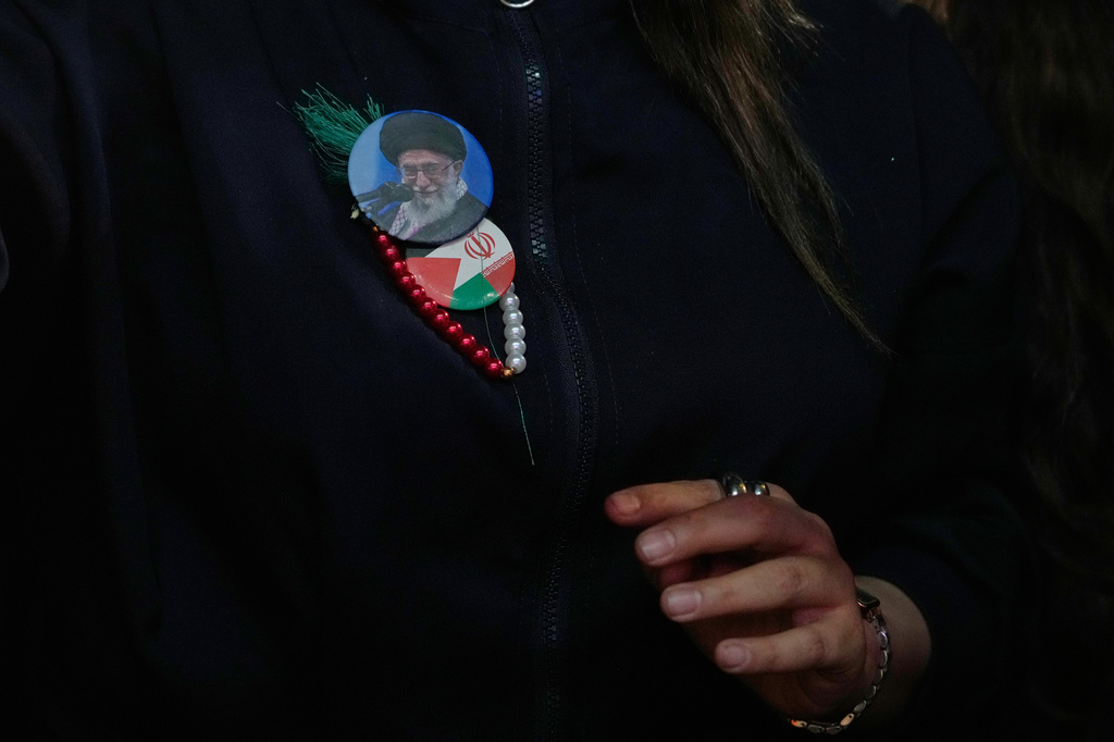 A government supporter wears badges showing a portrait of the slain Iranian Supreme Leader Ayatollah Ali Khamenei, and Iranian and Palestinian flags during a pro-government gathering at Islamic Revolution Square in Tehran, Iran, Wednesday, May 13, 2026. (AP Photo/Vahid Salemi)