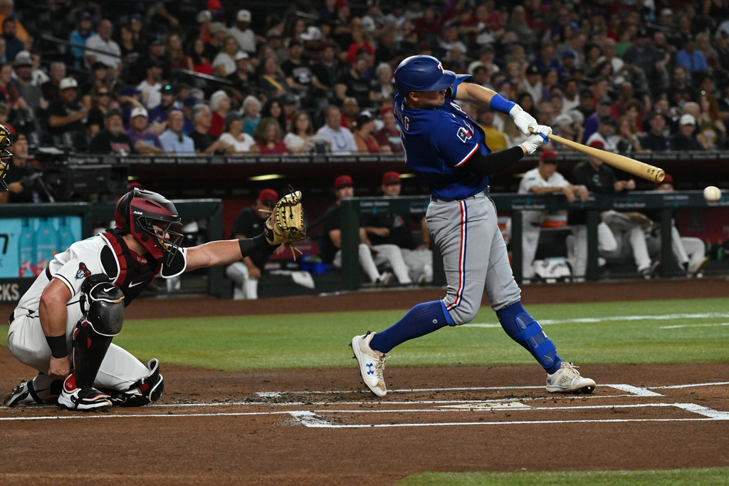 Texas Rangers' Josh Jung, right, makes contact off a pitch by Diamondbacks' Pitcher Eduardo Rodriguez during the first inning of a baseball game, Sunday, Sept. 13, 2026, in Phoenix. (AP Photo/Caitlin O'Hara)