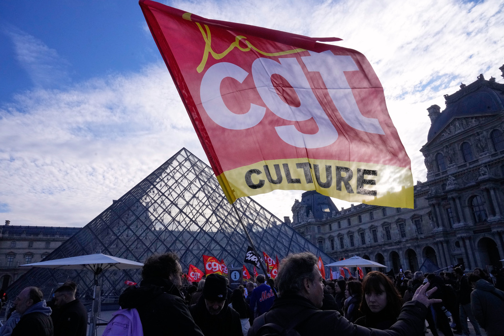 Workers display an union flag outside the Louvre museum after they voted to strike for the day over working conditions and other complaints, Monday, Dec. 15, 2025 in Paris. (AP Photo/Michel Euler)