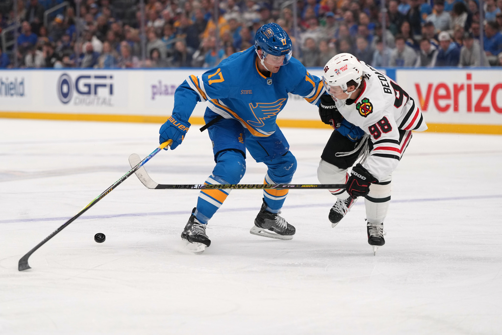 St. Louis Blues' Cam Fowler (17) and Chicago Blackhawks' Connor Bedard (98) battle for a loose puck during the second period of an NHL hockey game Wednesday, Oct. 15, 2025, in St. Louis. (AP Photo/Jeff Roberson)