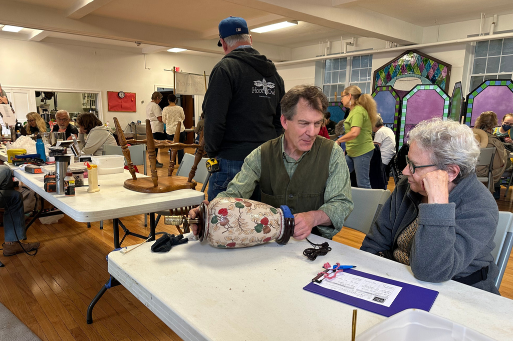 Wood repair coach Erik Hoover helps fix a lamp at a Repair Café in New Paltz, N.Y., May 23, 2026. (AP Photo/Michael Weissenstein)