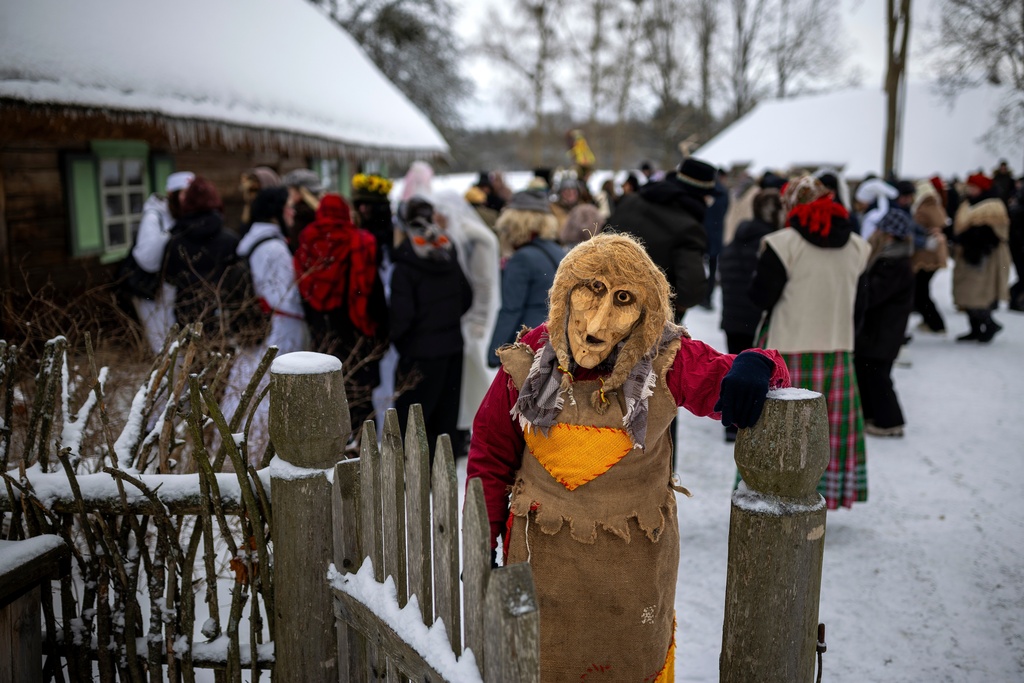 A woman wearing a traditional carnival mask takes part in Shrovetide celebrations in the village of Rumsiskes, some 89 kilometers (56 miles) north of Vilnius, Lithuania, Saturday, Feb. 14, 2026. (AP Photo/Mindaugas Kulbis)