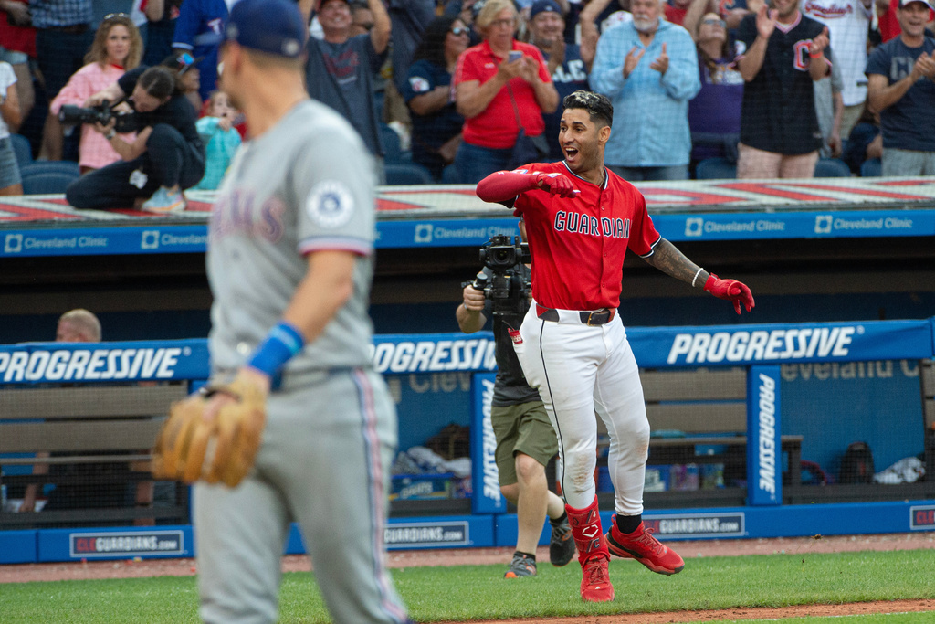 Texas Rangers' Josh Jung, foreground looks back as Cleveland Guardians' Brayan Rocchio celebrates his walk off three-run home run during the tenth inning of a baseball game, Sunday, Sept. 28, 2025, in Cleveland. (AP Photo/Phil Long)