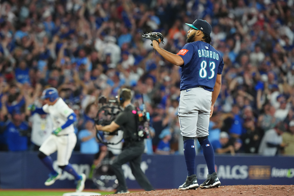 Seattle Mariners pitcher Eduard Bazardo (83) looks on as Toronto Blue Jays' George Springer, back left, rounds the bases after hitting a three-run home run during the seventh inning in Game 7 of baseball's American League Championship Series in Toronto, Monday, Oct. 20, 2025. (Frank Gunn/The Canadian Press via AP)