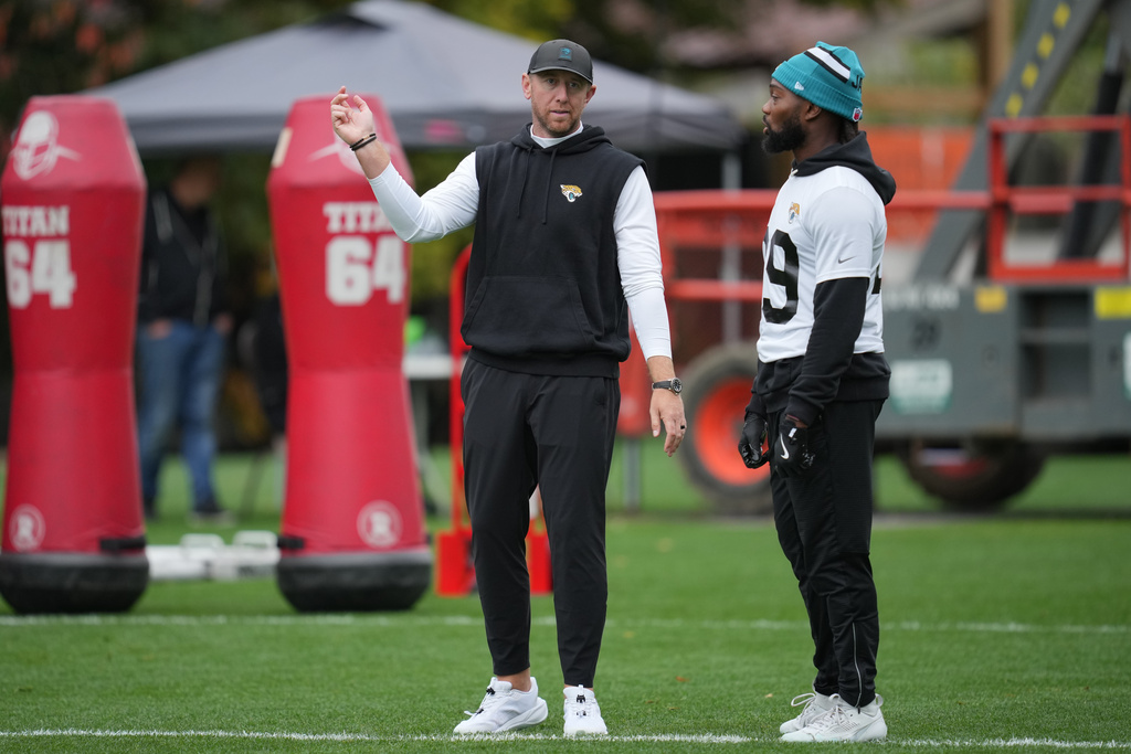 Jacksonville Jaguars head coach Liam Coen, left, talks to safety Eric Murray (29) during an NFL football practice at The Grove in Watford, England, Wednesday, Oct. 15, 2025. (AP Photo/Kin Cheung)