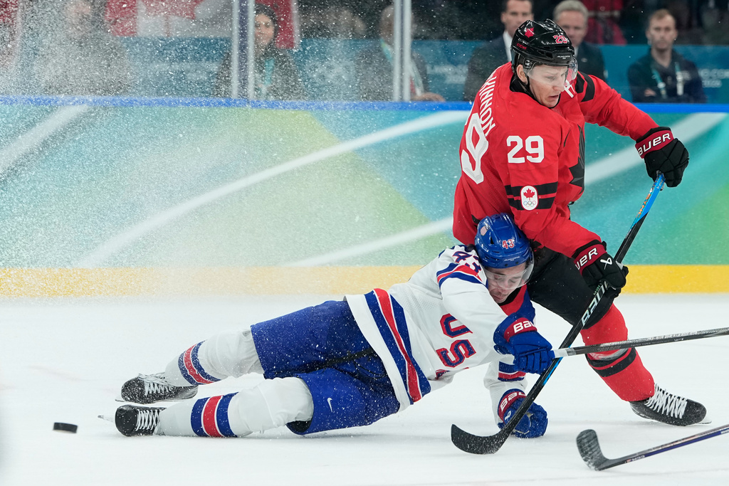 United States' Quinn Hughes (43) and Canada's Nathan MacKinnon (29) battle for the puck during a men's ice hockey gold medal game between Canada and the United States at the 2026 Winter Olympics, in Milan, Italy, Sunday, Feb. 22, 2026. (AP Photo/Petr David Josek)