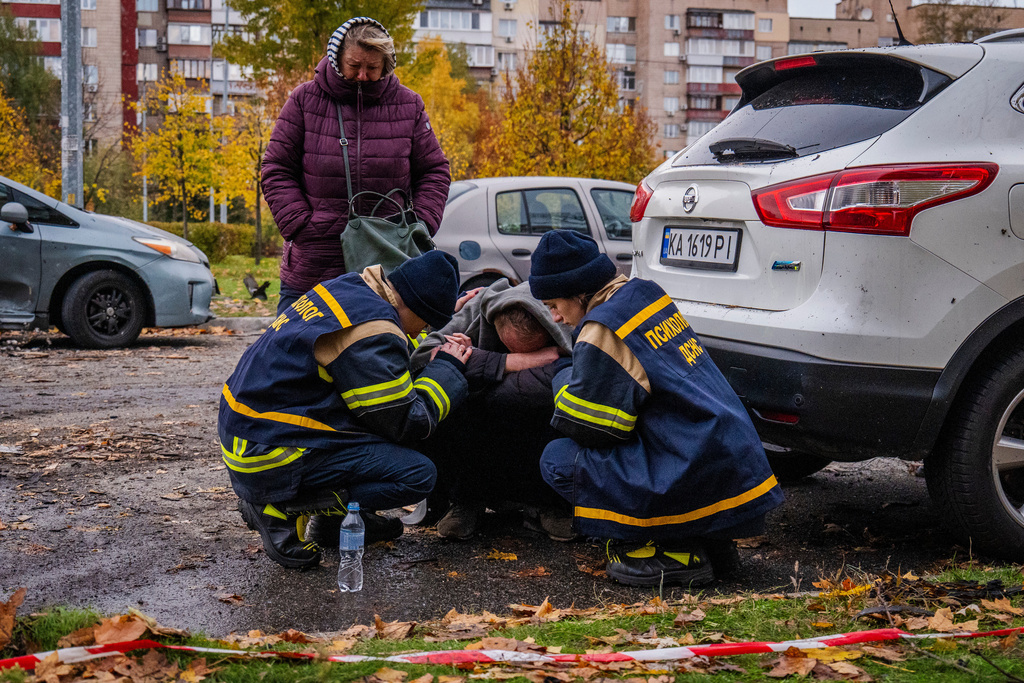 Emergency workers comfort a man who lost his son in Russia's drone attack that hit residential buildings in Kyiv, Ukraine, Sunday, Oct. 26, 2025. (AP Photo/Dan Bashakov)