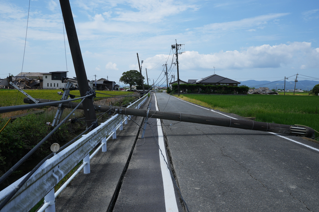 An electric pole is seen fallen across a street near damaged houses in Hikawa, southern Japan, Thursday, July 30, 2026, two days after an earthquake hit the area. (AP Photo/Hiro Komae)
