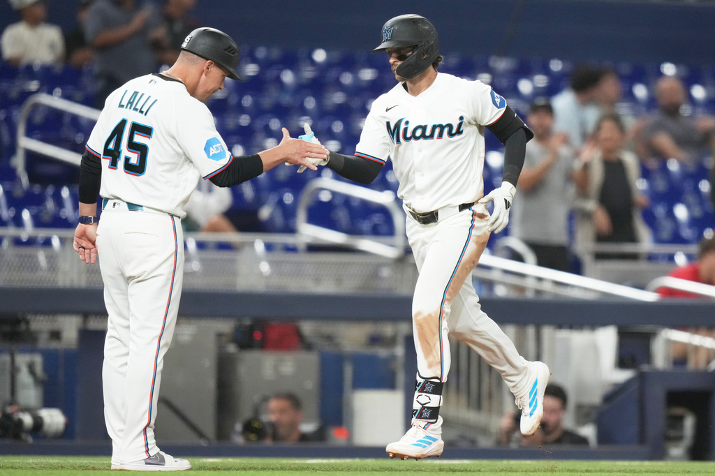 Miami Marlins' Connor Norby, right, is met by third base coach Blake Lalli (45) after hitting solo home run during the seventh inning of a baseball game against the Cincinnati Reds, Wednesday, April 8, 2026, in Miami. (AP Photo/Lynne Sladky)