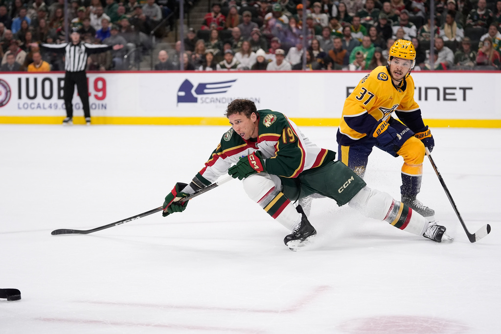 Minnesota Wild center Tyler Pitlick (19) reaches for his puck after losing his helmet as Nashville Predators defenseman Nick Blankenburg (37) follows during the first period of an NHL hockey game, Tuesday, Nov. 4, 2025, in St. Paul, Minn. (AP Photo/Abbie Parr)