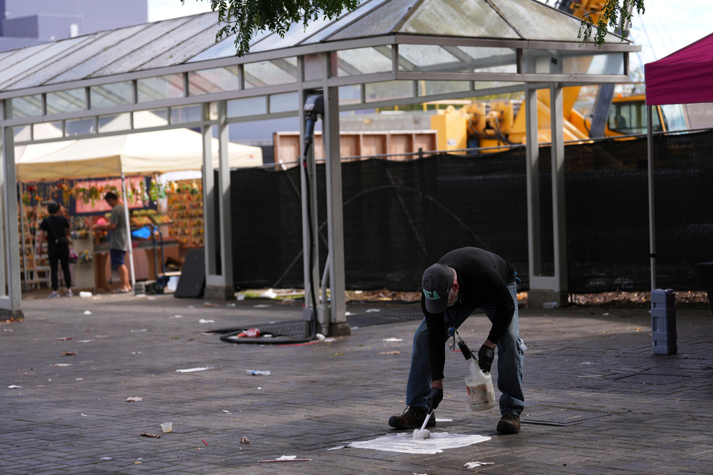 A worker cleans blood off the pavement the day after a shooting at Seattle Center during the Bite of Seattle food festival, Monday, July 27, 2026. (AP Photo/Lindsey Wasson)