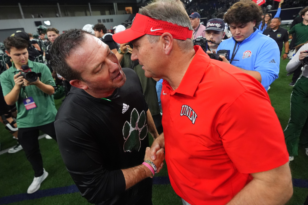 Ohio interim head coach John Hauser, left, shakes hands with UNLV head coach Dan Mullen after the Frisco Bowl NCAA college football game Tuesday, Dec. 23, 2025, in Frisco, Texas. (AP Photo/LM Otero)