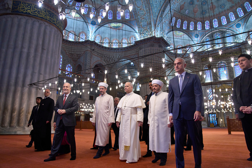 FILE - Pope Leo XIV, center, walks with Muezzin Musa Asgın Tunca, third from left, Istanbul's Mufti Emrullah Tuncel, fourth from left, the Imam of Mosque Sultanahmet Fatih Kaya, sixth from left, and Turkish Minister for Culture and Tourism Mehmet Nuri Ersoy, seventh from left, during a visit to the Mosque in Istanbul, Saturday, Nov. 29, 2025. (AP Photo/Domenico Stinellis, File)