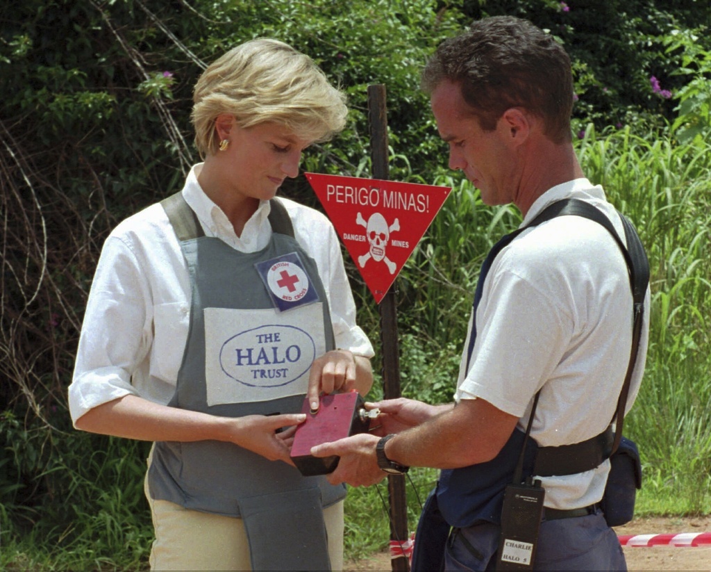 FILE - Diana, Princess of Wales, left, uses a remote switch to trigger the detonation of some explosive ordinance dug up by mine sweepers in Huambo, central Angola, Jan. 15, 1997. (AP Photo/Giovanni Diffidenti, File)