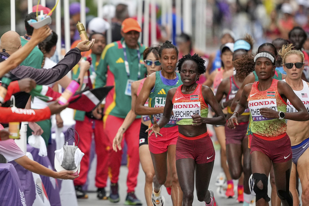 Kenya's Peres Jepchirchir and Kenya's Jackline Cherono are offered refreshments at a drinks station in the women's marathon at the World Athletics Championships in Tokyo, Sunday, Sept. 14, 2025. (AP Photo/Hiro Komae)