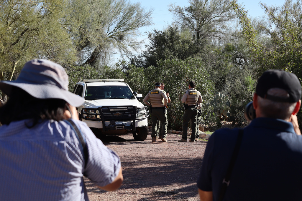 Photographers take images of sheriff's deputies outside the home of Nancy Guthrie in Tucson, Ariz., Sunday, Feb. 22, 2026. (AP Photo/Felicia Fonseca)