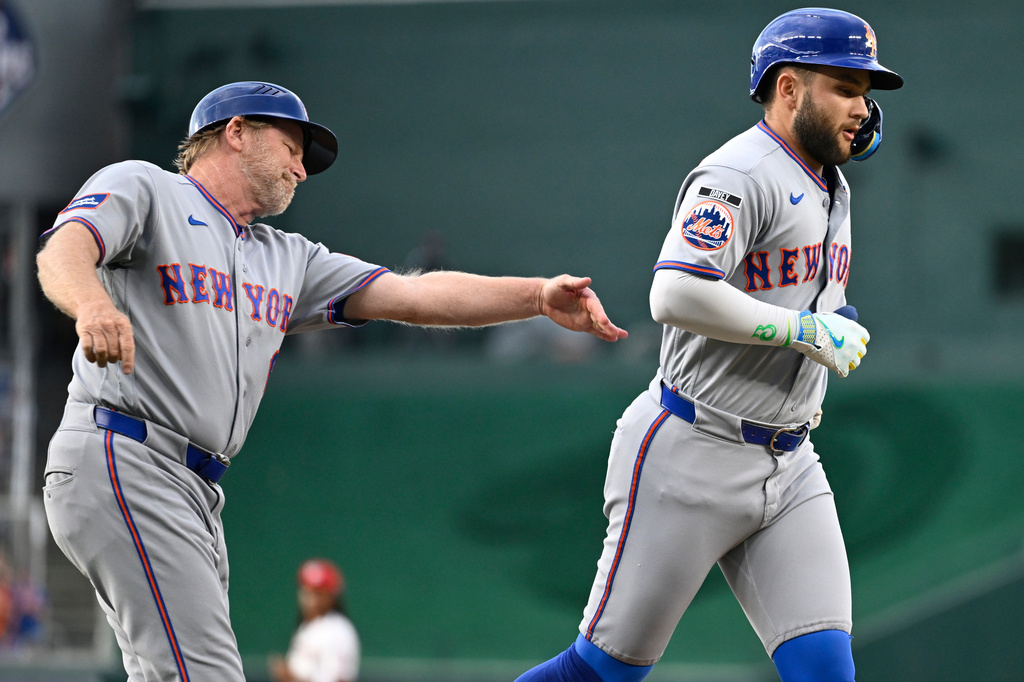 New York Mets third base coach Tim Leiper, left, congratulates Bo Bichette on a two run home run during the first inning of a baseball game against the Washington Nationals, Tuesday, May 19, 2026, in Washington. (AP Photo/John McDonnell)