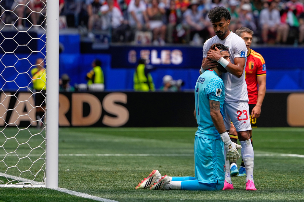Iran's Ramin Rezaeian (23) embraces Alireza Beiranvand during the World Cup Group G soccer match between Belgium and Iran in Inglewood, Calif., near Los Angeles, Sunday, June 21, 2026. (AP Photo/Mark J. Terrill)