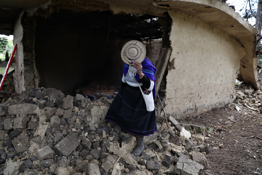A Misak Indigenous woman stands amid the ruins of a house torn down during clashes with the Nasa community over a land dispute in Silvia, Colombia, Friday, May 22, 2026. (AP Photo/Santiago Saldarriaga)