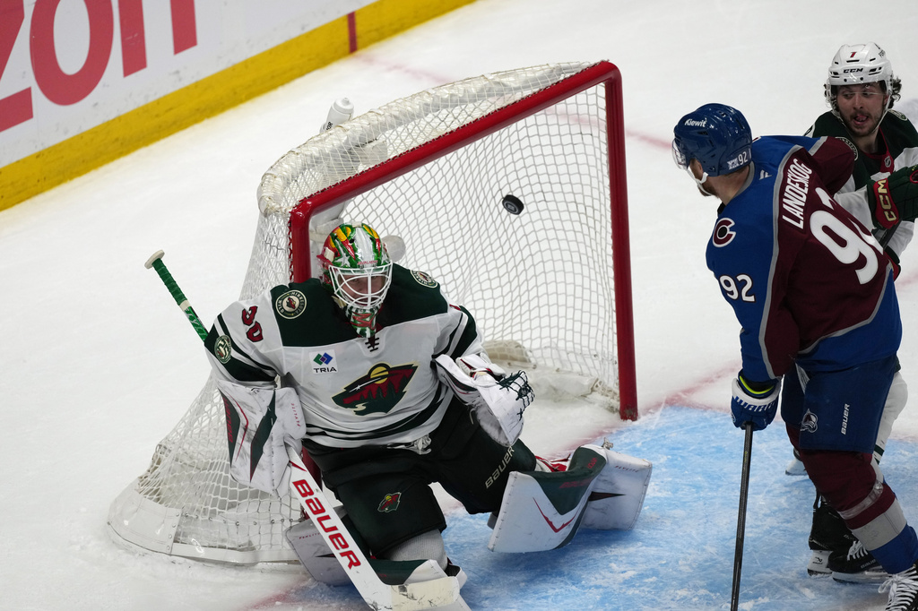 Minnesota Wild goaltender Jesper Wallstedt, left, allows a goal by Colorado Avalanche center Nathan MacKinnon as left wing Gabriel Landeskog looks on in the third period of Game 5 of an NHL Stanley Cup hockey second-round playoff series, Wednesday, May 13, 2026, in Denver. (AP Photo/David Zalubowski)