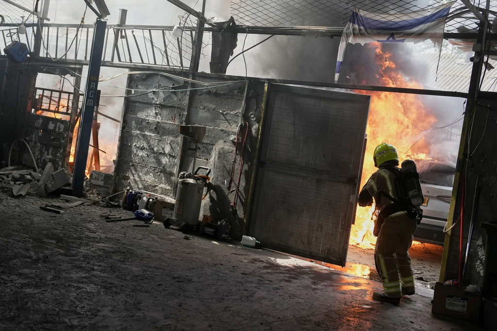 A firefighter battles flames at a damaged workshop after an alert of incoming missiles in Petah Tikva, Israel, Tuesday, March 31, 2026. (AP Photo/Oded Balilty)