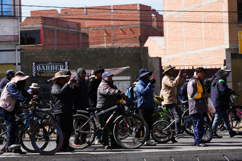 Residentes take pictures at police clearing a highway blocked by protesters after President Rodrigo Paz declared a state of emergency in El Alto, Bolivia, Saturday, June 20, 2026. (AP Photo/Juan Karita)