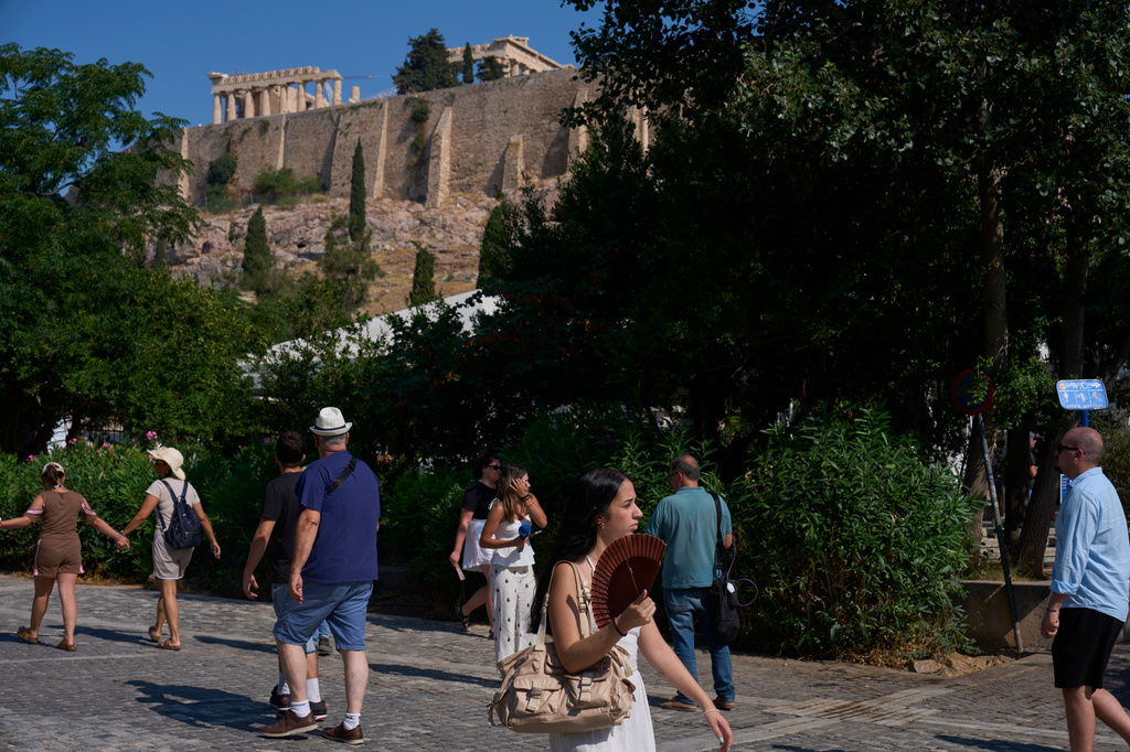 Tourists walk near the Acropolis in Athens, Greece, Tuesday, July 21, 2026, after two tourists were stabbed and injured nearby in an attack on a pedestrian street near the entrance to the archaeological site. (AP Photo/Petros Giannakouris)