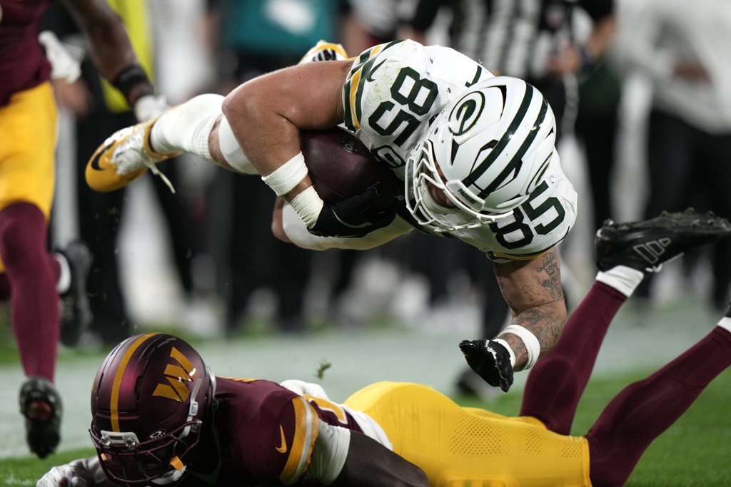 Green Bay Packers tight end Tucker Kraft (85) sails over Washington Commanders safety Quan Martin during the first half of an NFL football game Thursday, Sept. 11, 2025, in Green Bay, Wis. (AP Photo/Morry Gash)