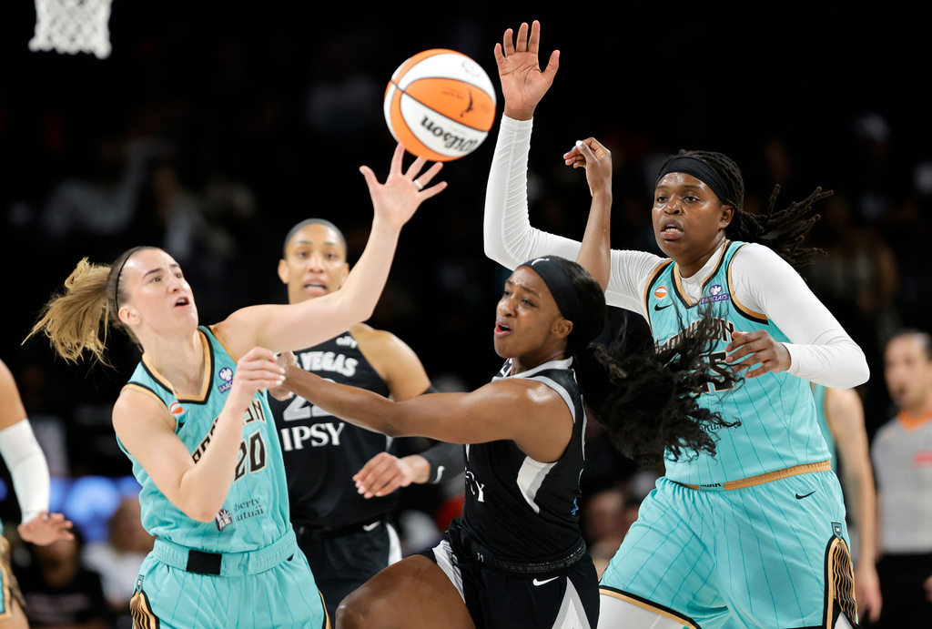 New York Liberty guard Sabrina Ionescu (20), Las Vegas Aces guard Jackie Young, center, and center Jonquel Jones (35) chase after a rebound during the first half of an WNBA basketball game Tuesday, June 23, 2026, in Las Vegas. (Steve Marcus/Las Vegas Sun via AP)