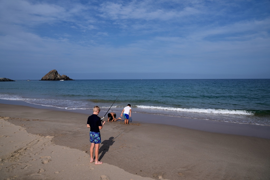 Young foreigners enjoy a day at the beach overlooking the Strait of Hormuz near Khor Fakkan, United Arab Emirates, Wednesday, March 11, 2026. (AP Photo/Altaf Qadri)