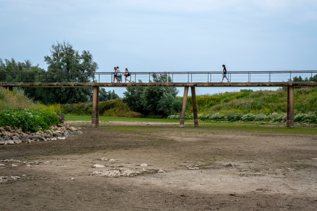 People walk across a footbridge over a dry river bed near Beusichem, Netherlands, Thursday, July 30, 2026, during drought conditions. (AP Photo/Patrick Post)